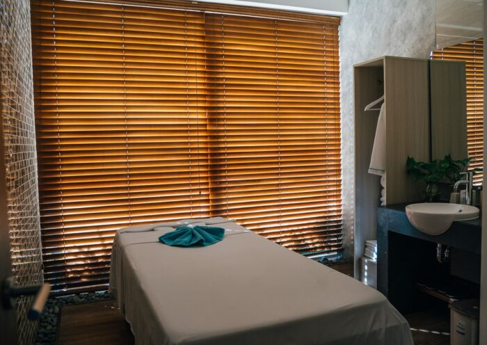 A serene spa treatment room with a massage table and wooden blinds