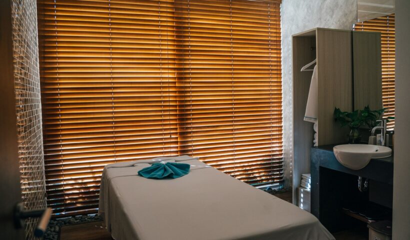 A serene spa treatment room with a massage table and wooden blinds