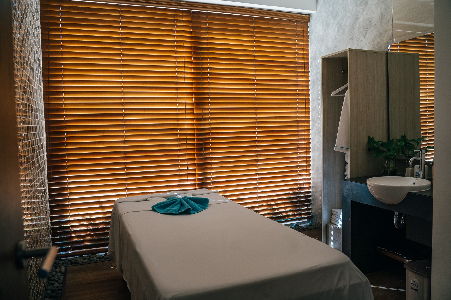A serene spa treatment room with a massage table and wooden blinds