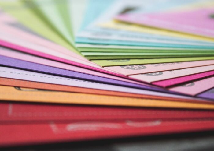 A close-up view of fanned out colorful paper sheets in various hues, representing printing materials.