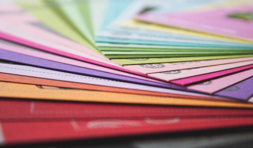 A close-up view of fanned out colorful paper sheets in various hues, representing printing materials.